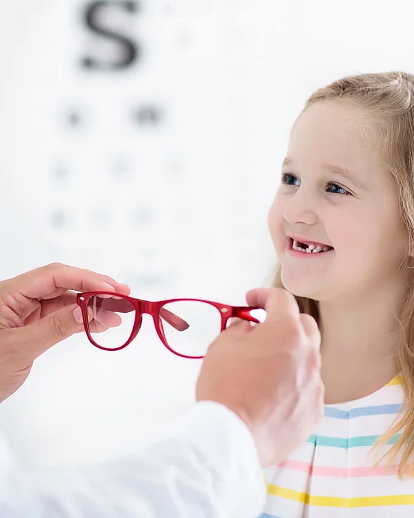 Kundenberater setzt Mädchen eine rote Brille auf